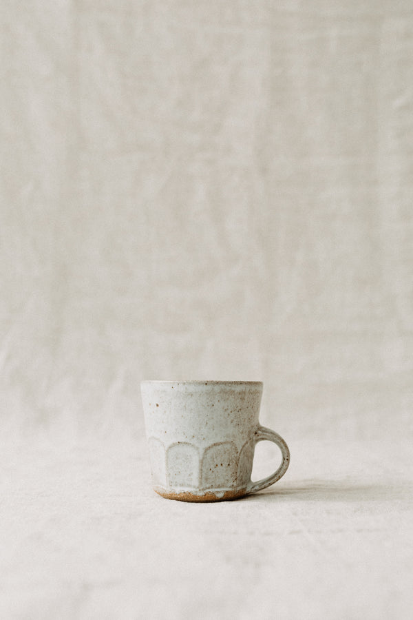 Small Handmade ceramic cup by Tim Lake. Made with a low handle and faceted at the bottom edge. Glazed with a grey dolomite glaze