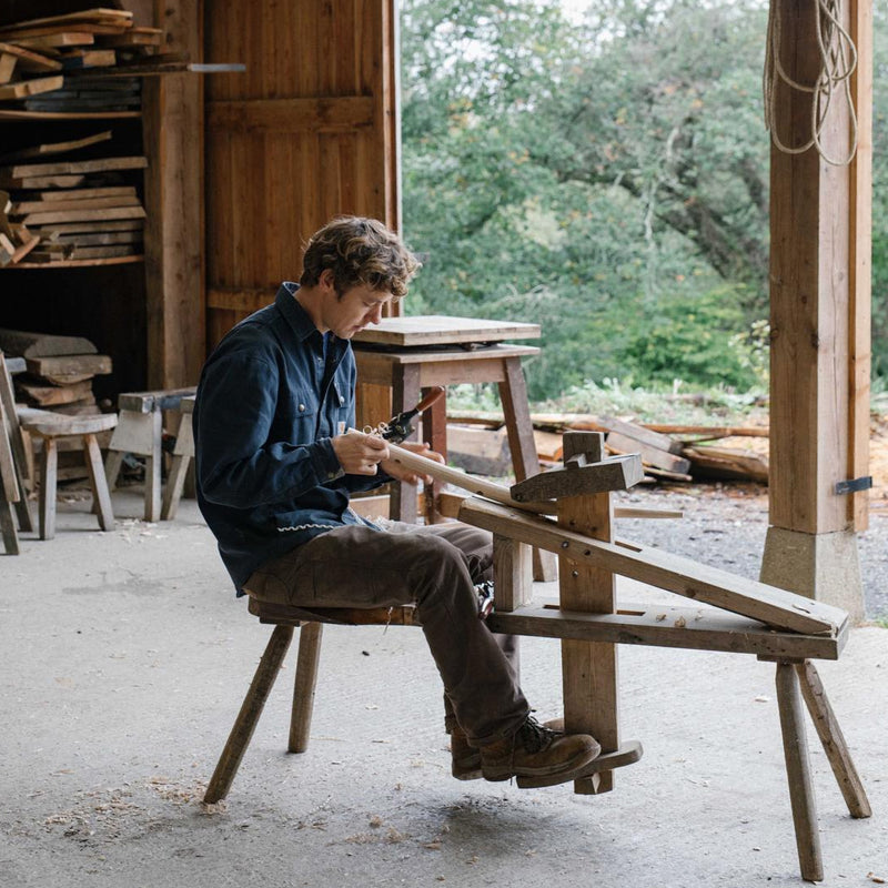 Ambrose Vevers in his workshop sitting at his lathe turning wood