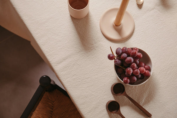 Handmade coffee scoops by Selwyn House on a table amongst other beautiful handmade objects and a bunch of grapes.